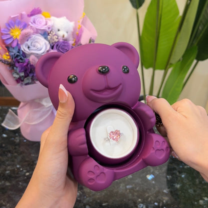 Blush pink heart ring inside hidden compartment of purple teddy bear rose box