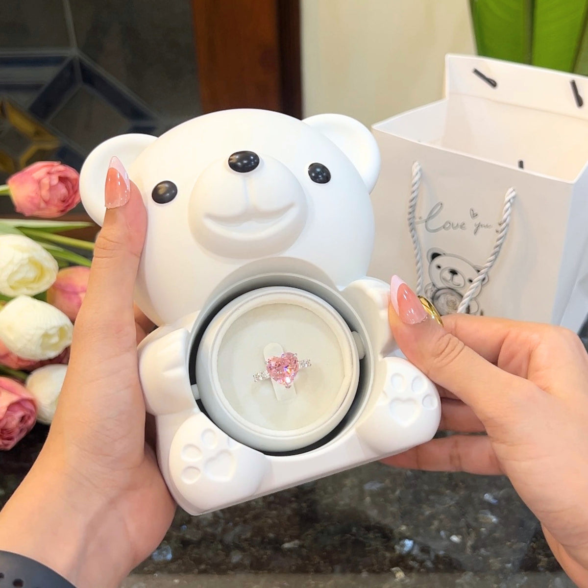 Blush heart ring inside hidden compartment of white teddy bear rose box