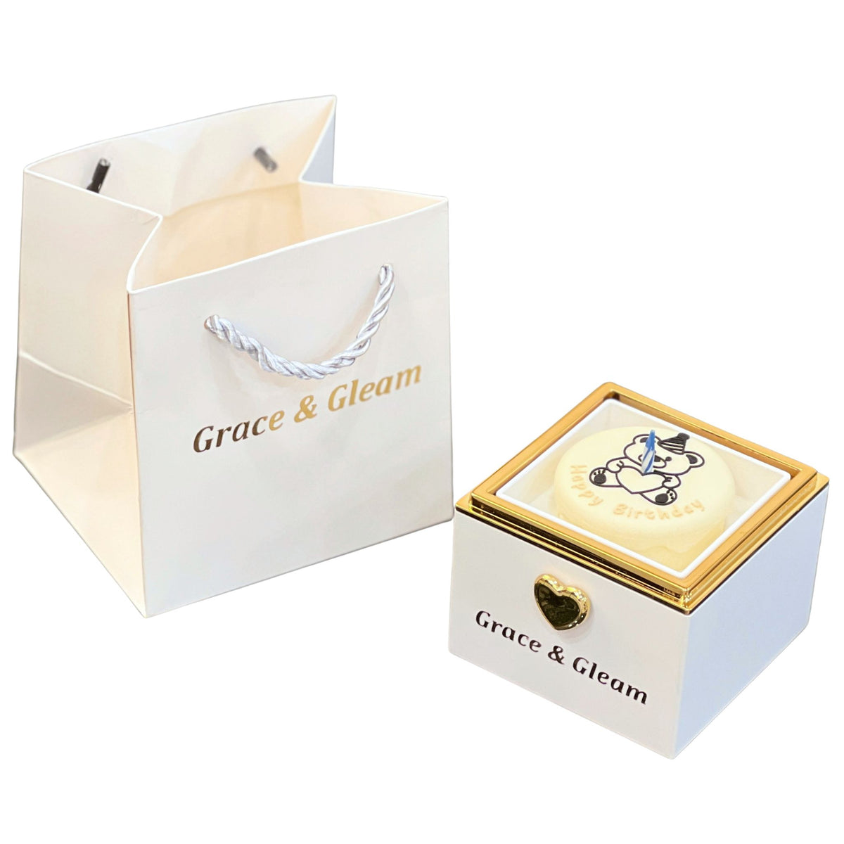 Candle-lit birthday box in white with Happy Birthday cake top, blue candle and Grace & Gleam gift bag