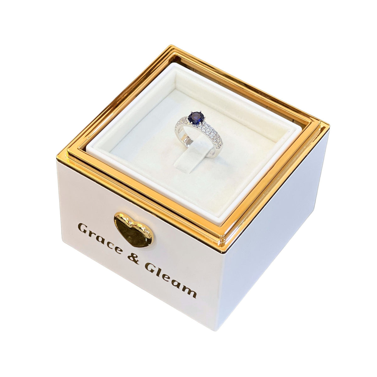 Ocean blue ring revealed inside white Grace & Gleam candle-lit birthday box with gold frame