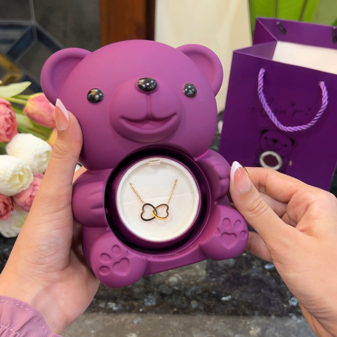 Double heart necklace inside hidden compartment of purple teddy bear rose box