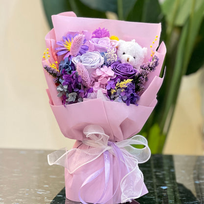 Purple preserved flower bouquet with a white teddy bear, wrapped and ribboned