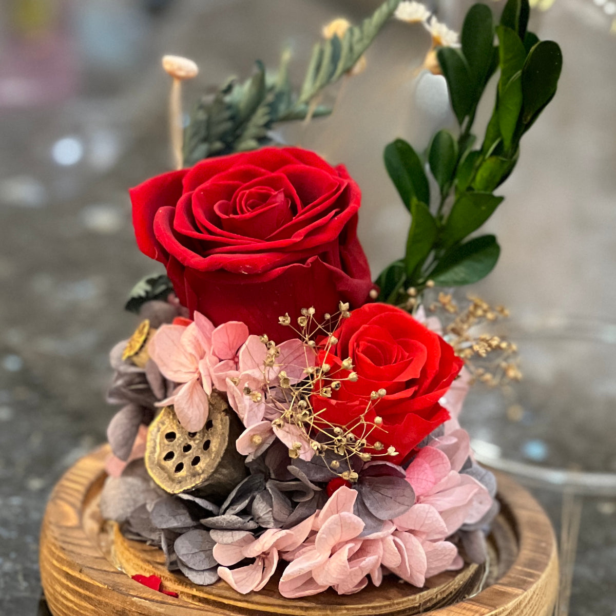 Close-up of preserved red roses with pink hydrangea, lotus pod and gypsophila