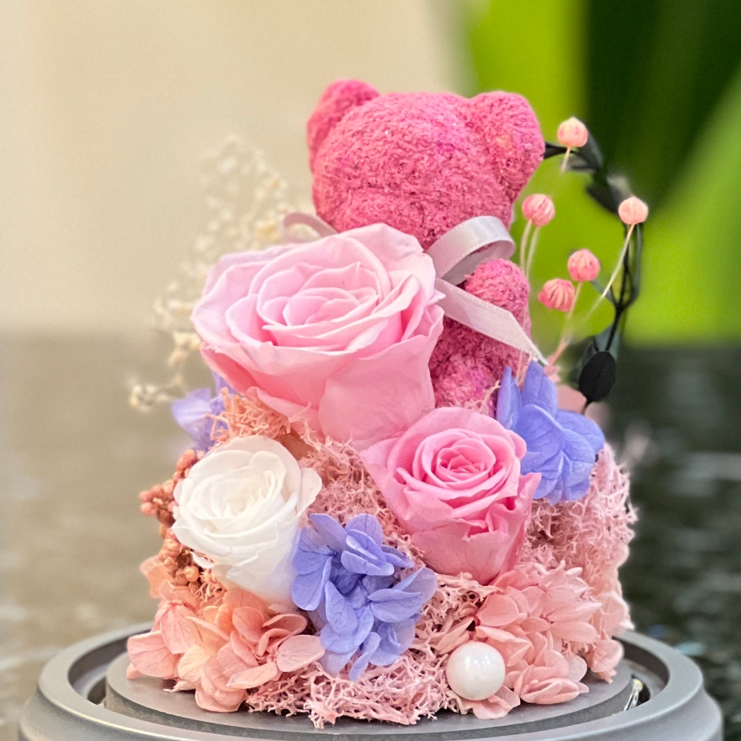 Close-up of a pink moss bear with preserved pink and white roses
