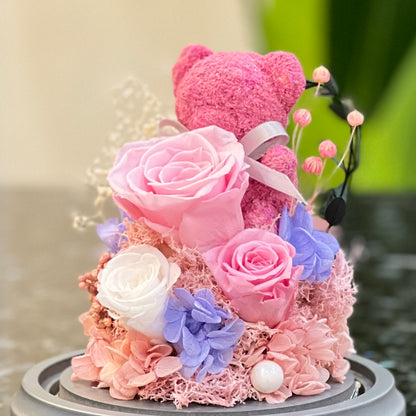 Close-up of a pink moss bear with preserved pink and white roses