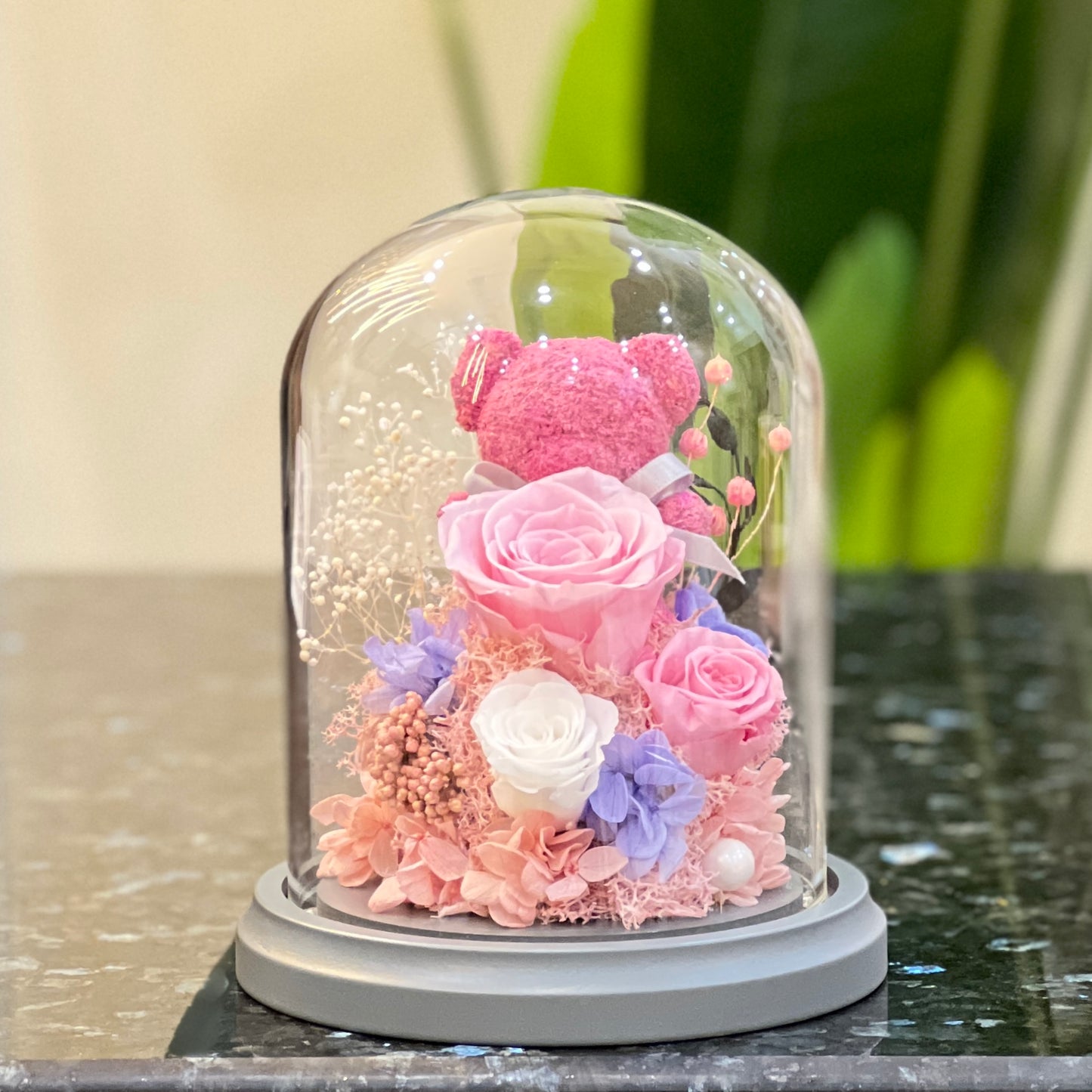 Front view of a pink moss bear with preserved roses in a glass dome