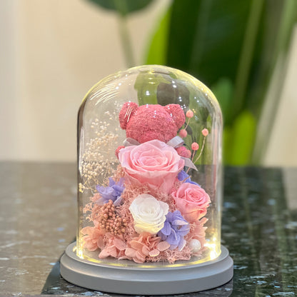 Pink rose bear with preserved roses glowing under a glass dome with LED on
