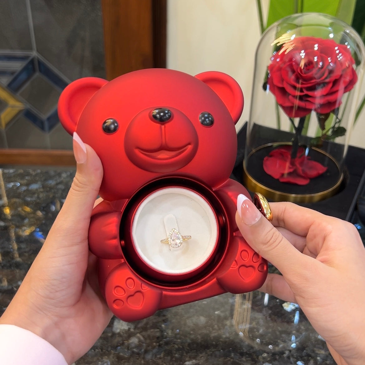 Gold drop ring inside hidden compartment of red teddy bear rose box
