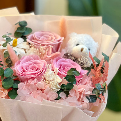 Preserved pink roses, hydrangea and dried flowers with a small white bear