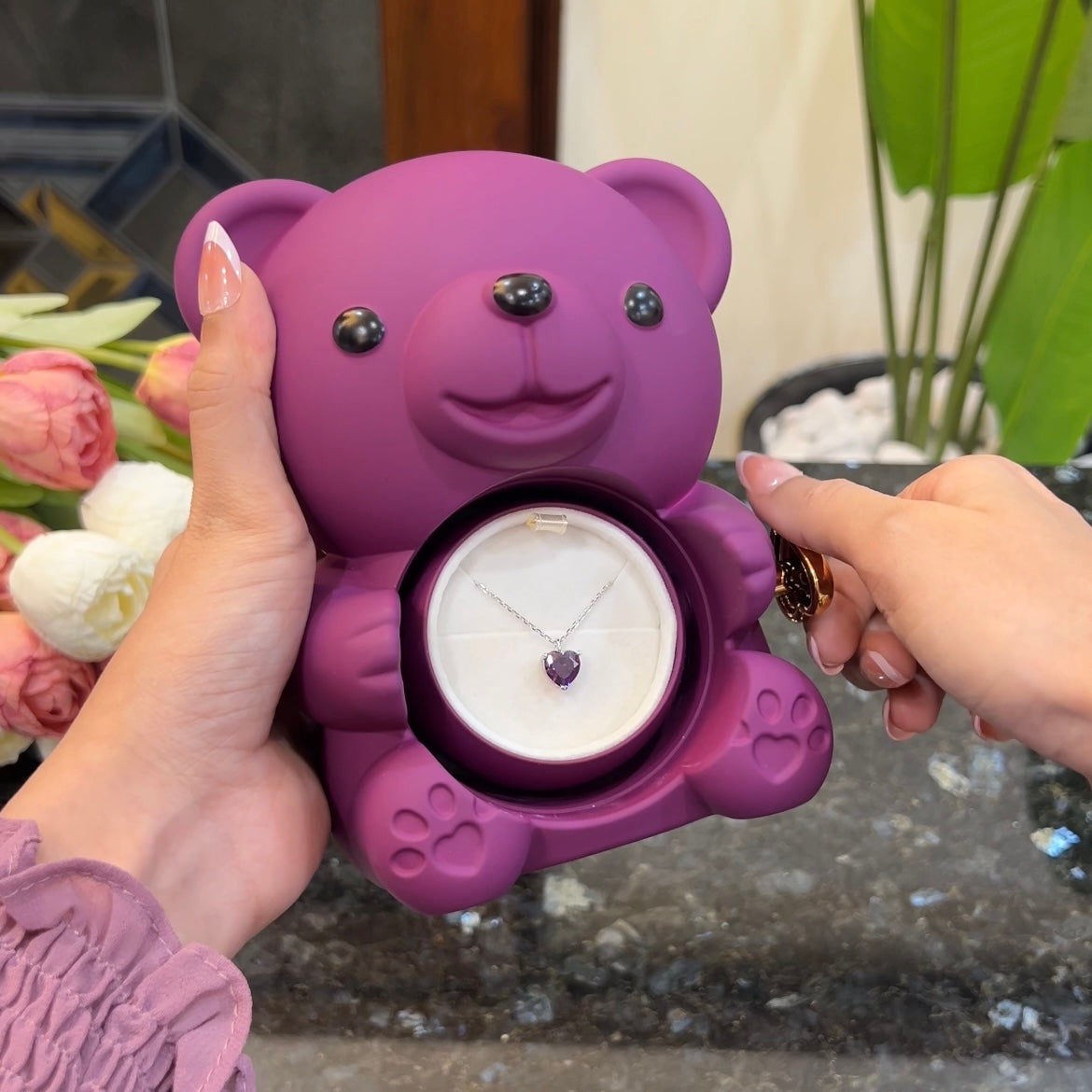 Purple heart pendant on silver chain inside hidden compartment of purple teddy bear rose box