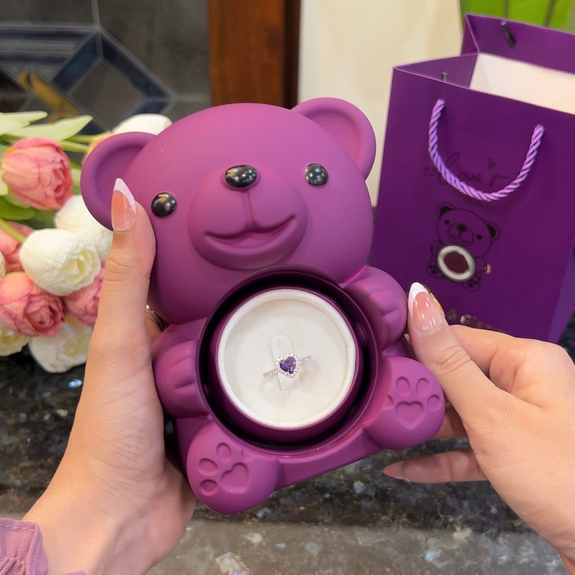 Purple heart ring inside hidden compartment of purple teddy bear rose box